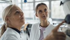 Two people in lab coats work with monitor