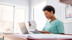 Healthcare worker looking at papers at a desk with a laptop