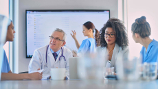 Healthcare workers meeting with large screen in background