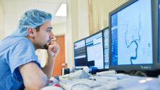 Healthcare worker in scrubs looking at medical image on screen