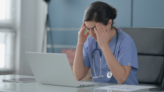 Frustrated physician documenting at laptop