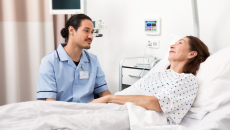 A nurse sitting beside a patient in bed