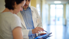 A radiologist showing a patient their x-ray report on a digital tablet