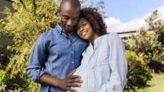 Pregnant person and partner embracing