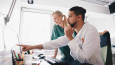 Healthcare worker pointing at a screen in conversation with colleague