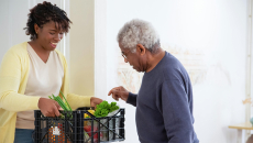 Woman holds a plastic delivery of prescription produce for an older man