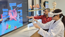 A medical student wearing a VR headset is learning the parts of the heart while being assisted by an instructor