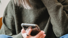 Mobile phone in the hands of a person in green sweater