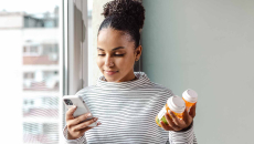 Person holding pill bottles and phone