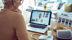 Cardiac patient talking to cardiologist on a telehealth call with monitor, medication and a sandwich on the table