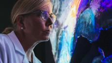 Person in lab coat looking at computer display