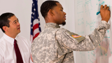 veteran draws on a whiteboard with a colleague