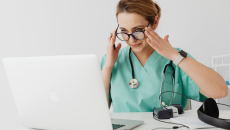 Doctor in scrubs setting up laptop for telehealth