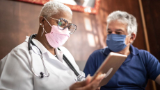 Doctor and patient in masks looking at a tablet