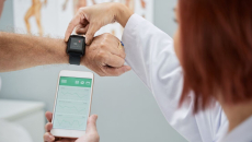 A doctor helping a patient set up a smartwatch and app.