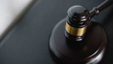 Black and gold gavel on a black table.