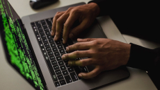 Hands on a laptop, and the screen shows code