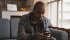 Man in gray on gray couch checks health records on a smartphone