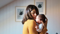 new mother in yellow holding infant