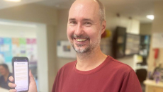 Dr Eamonn Eeles holding a mobile phone showing the electronic tool for assessing delirium causes