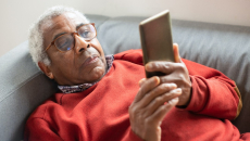 Person lies on couch reading from mobile phone