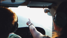 In a plane, a copilot points to a destination on the horizon.