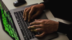 Hands typing on a laptop showing code only