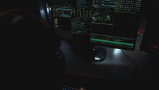 monitor on dark desktop shows multiple screens of data
