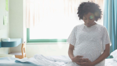 Pregnant person sits on hospital bed