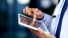 Close-up of a clinician's hands reviewing patient data on tablet