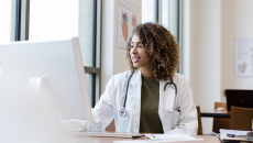 A doctor reviewing a patient's record on a desktop computer