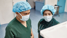 Two surgeons checking on an operation's progress through a digital monitor