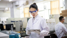A lab scientist reviewing data in a digital tablet
