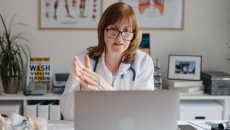 A doctor conducting a remote teleconsultation using a laptop