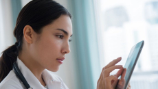 A doctor using a digital tablet to review a patient's file