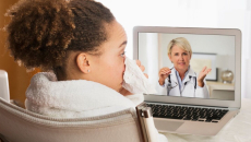 A sick patient consulting with a doctor via video call on a laptop