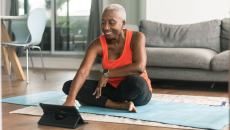 Person sits on a yoga mat with a tablet