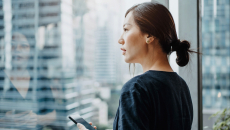 Person with smartphone looking out the window