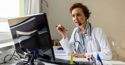 A doctor wearing a headset with a microphone in virtual consultation with a patient