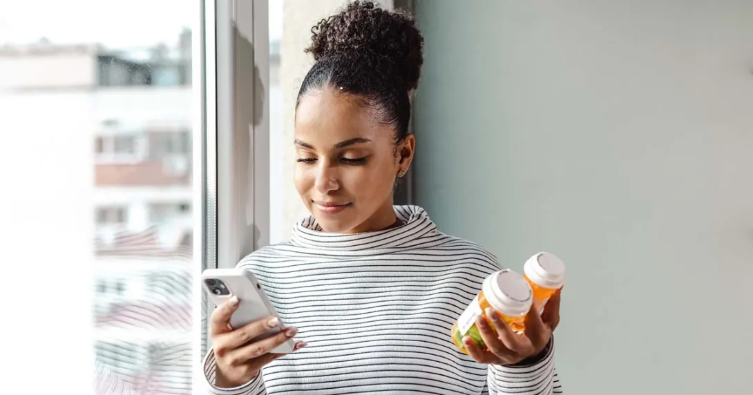 Smartphone user holding a pill bottle Smartphone user holding a pill bottle