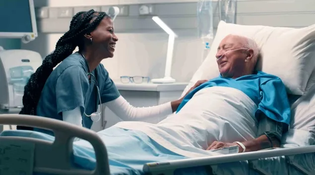 Healthcare worker talking to patient in hospital bed Healthcare worker talking to patient in hospital bed