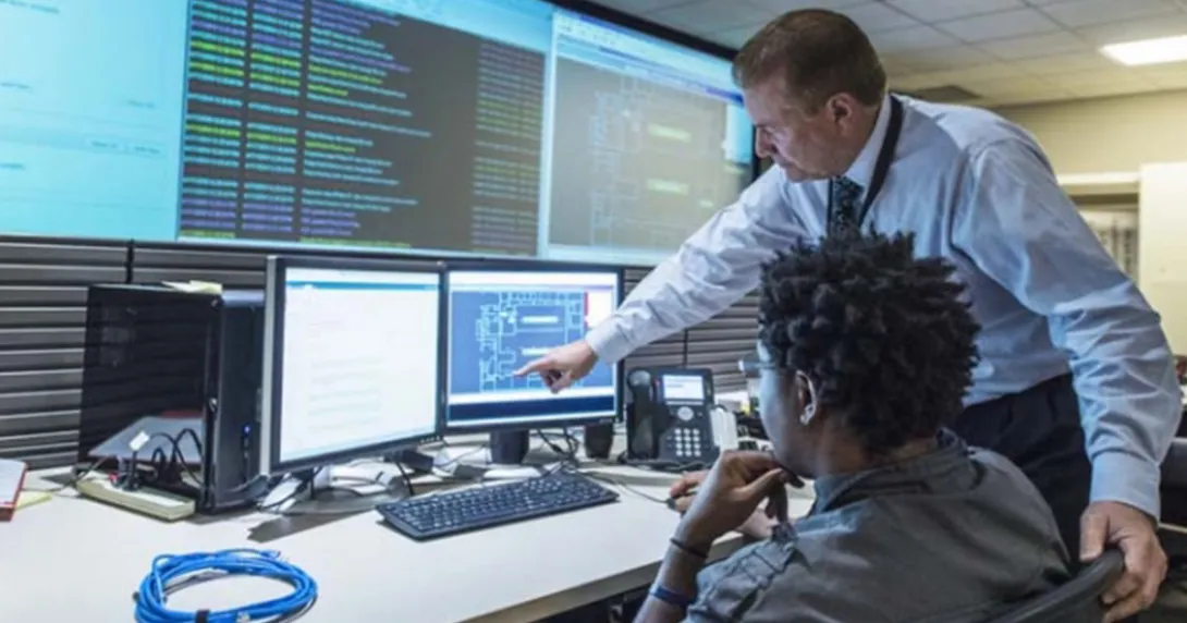 Two people examine screens with data displayed Two people examine screens with data displayed