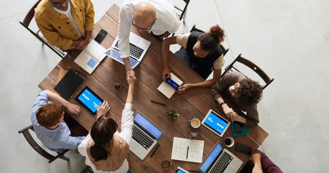 Two people shake hands during a meeting at a table Two people shake hands during a meeting at a table