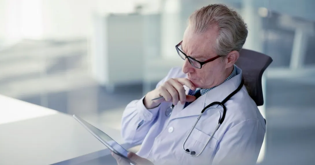 A doctor reviewing a patient's record on a digital tablet. A doctor reviewing a patient's record on a digital tablet.