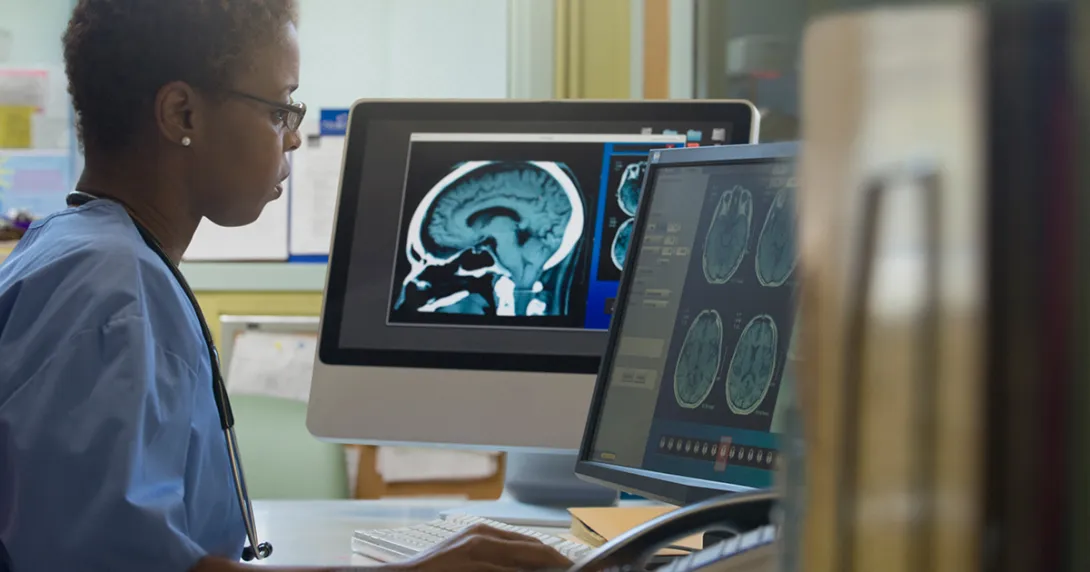 Healthcare worker with MRI image working on a computer