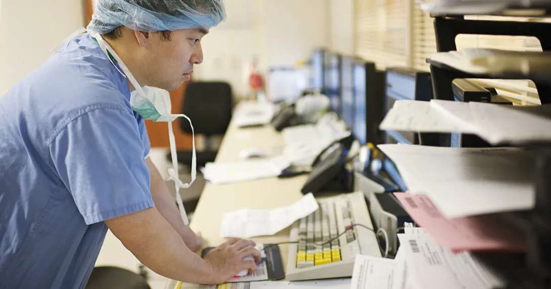 A doctor looking for patient data on a desktop computer