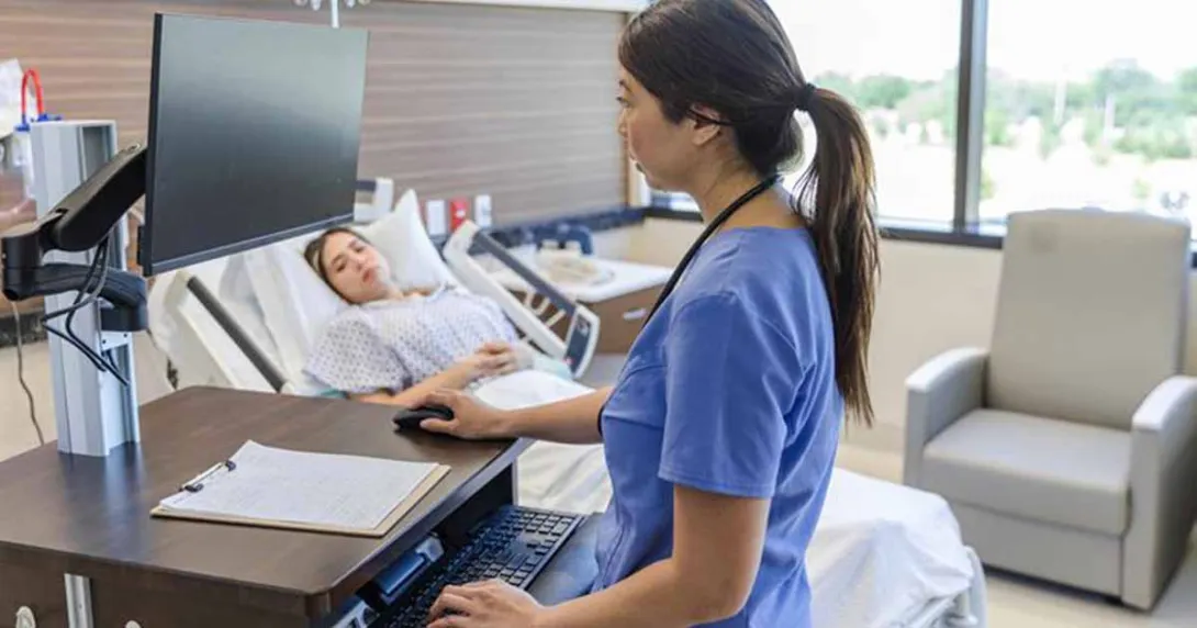 Nursing using laptop in hospital room with patient Nursing using laptop in hospital room with patient