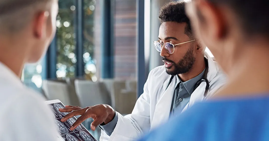 Healthcare professionals examine a brain scan on a tablet