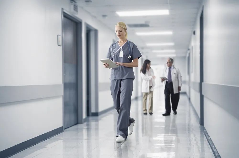 Healthcare worker walking in a hospital with tablet