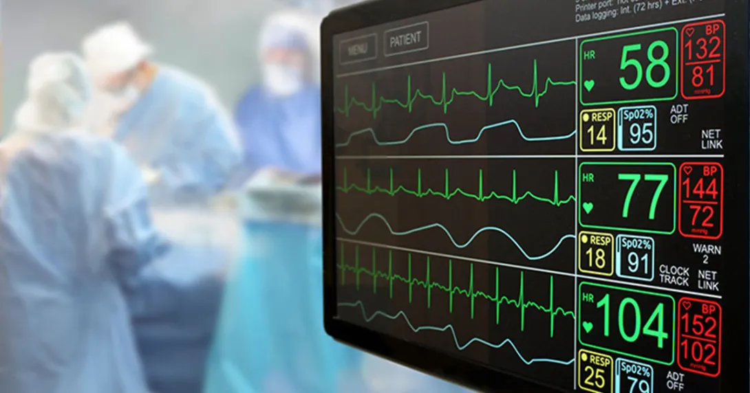 ECG monitor appears in the foreground and surgeons appear to be operating in the background.